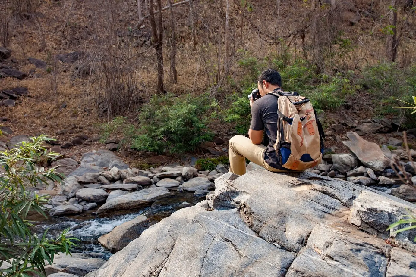 Ein Wanderer, der auf einem Felsen ein Foto macht.