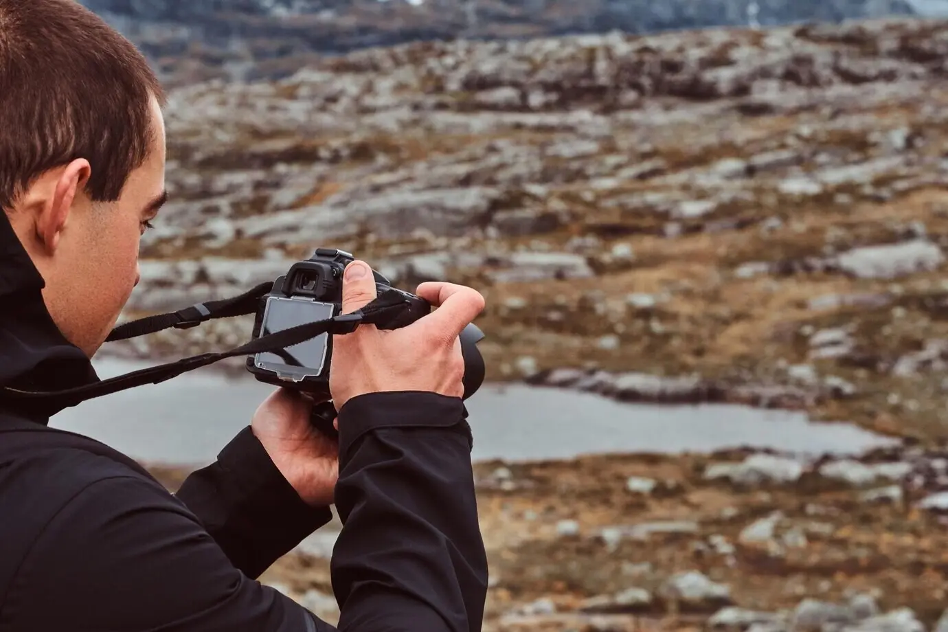 Naturfotograf und Tourist mit Kamera fotografiert stehend auf einem Berg. Norwegen.