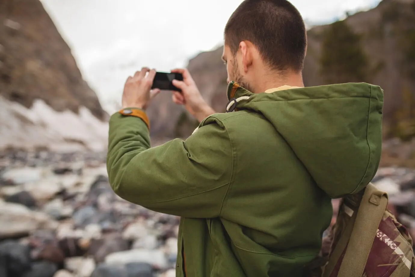 Junger Hipster-Mann, der mit dem Smartphone Fotos macht, wilde Natur, Winterurlaub, Wandern.